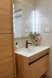 a bathroom sink with a mirror and a vase of flowers at Edulis 1 in Arenas de San Pedro +34 photos