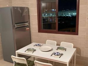 una mesa blanca con sillas y platos y un refrigerador en appartement équipé, en Tánger