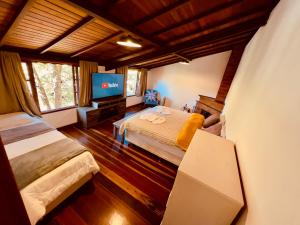 une chambre avec deux lits et une télévision à écran plat dans l'établissement Casa da Mel, à Itatiaia
