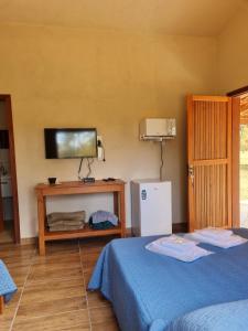 a bedroom with two beds and a tv on the wall at Pousada Águas da Canastra in Vargem Bonita
