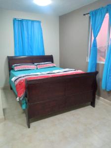 a bedroom with a wooden bed with blue curtains at Departamentos velasco in Tijuana