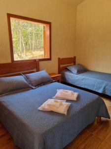 two beds in a room with towels on them at Pousada Águas da Canastra in Vargem Bonita