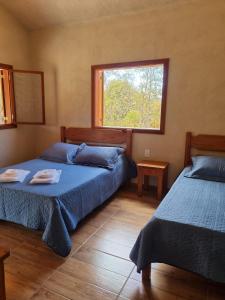 1 dormitorio con 2 camas y ventana en Pousada Águas da Canastra, en Vargem Bonita