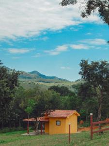 una pequeña casa amarilla en medio de un campo en Pousada Águas da Canastra, en Vargem Bonita
