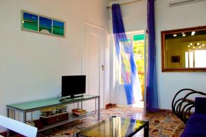 uma sala de estar com uma mesa de vidro e uma televisão em Le Terrazze sulle Eolie em Caronia Marina
