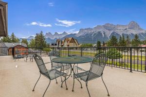 un patio con mesa, sillas y montañas en Northwinds Hotel Canmore en Canmore