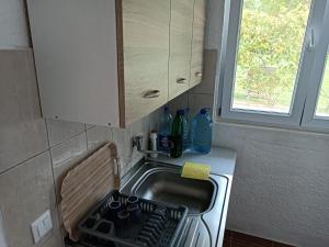 uma pequena cozinha com um lavatório e uma janela em cottage h & i em Jajce