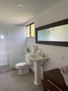 a white bathroom with a toilet and a sink at Espectacular casa campestre in Pereira