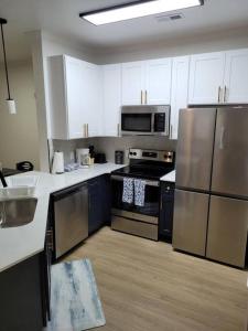 una cocina con electrodomésticos de acero inoxidable y armarios blancos en South Charlotte’s Cozy & Modern en Charlotte
