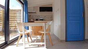 een tafel en stoelen in een keuken met een blauwe deur bij Maisonnette entière et privée, 600m de la gare in Margny-lès-Compiègne