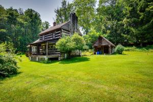 an old house in a field of green grass at Historic Morrisdale Area Cabin with Deck and Fireplace 