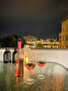 zwei Weingläser auf einem Tisch mit einer Flasche Wein in der Unterkunft Danube view Artapartment with balcony in Budapest