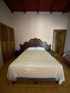 a bedroom with a large bed with a wooden headboard at Hotel y Balneario Villa Paraíso in Catacamas