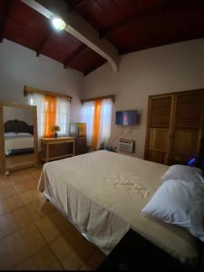 a bedroom with a large white bed and a television at Hotel y Balneario Villa Paraíso in Catacamas