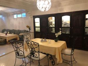 a dining room with two tables and chairs and a chandelier at Villa piscine Agadir in Agadir