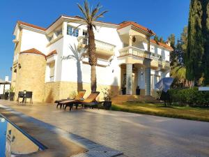 Villa piscine Agadir في أغادير: منزل أبيض كبير مع مقاعد أمامه