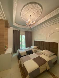 een slaapkamer met 2 bedden en een kroonluchter bij Villa piscine Agadir in Agadir