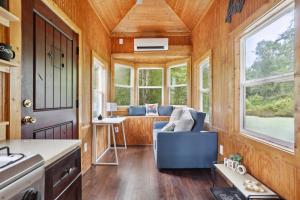 布拉塞爾頓的住宿－Pendergrass Tiny Home Cabin on Pond with Fire Pit!，一间小房子,配有蓝色的沙发和一间客厅