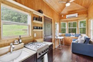 a kitchen in a tiny house with a stove at Pendergrass Tiny Home Cabin on Pond with Fire Pit! in Braselton