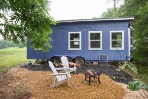 布拉塞爾頓的住宿－Pendergrass Tiny Home Cabin on Pond with Fire Pit!，坐在院子里的蓝色小房子