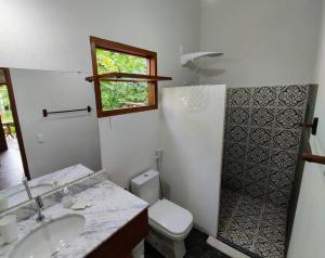 Un baño con inodoro, lavabo y ventana. en CasAmar Pé na Areia em Condomínio Beira Mar, en Serra Grande