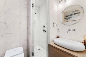 a white bathroom with a shower and a sink at Furnished and Meticulously Renovated 3-bedroom, 2-bathroom Loft in New York
