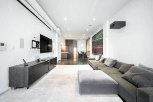 ein großes Wohnzimmer mit einem Sofa und einem TV in der Unterkunft Furnished and Meticulously Renovated 3-bedroom, 2-bathroom Loft in New York