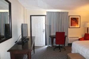 Habitación de hotel con cama y escritorio con TV. en Historic Cow Palace Inn, en Lamar