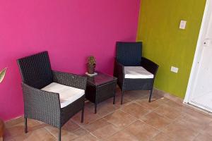 Habitación con 3 sillas, mesa y pared rosa en Colombia 147, en Puerto Vallarta
