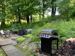 a barbecue in a garden next to a wooden deck at Sadawga Springs Retreat in Whitingham