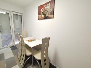 een eetkamer met een witte tafel en stoelen bij Apartman Lola Ruža in Zrenjanin