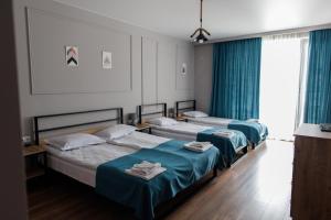 two beds in a room with blue curtains at ALOFT in Kazbegi