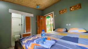 a bedroom with a bed with a bottle of water on it at Wooden Kemiren Homestay Banyuwangi in Banyuwangi