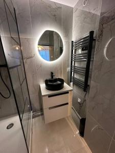 La salle de bains est pourvue d'un lavabo et d'un miroir. dans l'établissement Charmant Appart Métro Proche Confort, à Bagnolet
