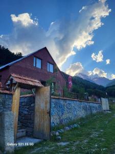 een huis met een houten poort en een stenen muur bij Peak House in Kazbegi