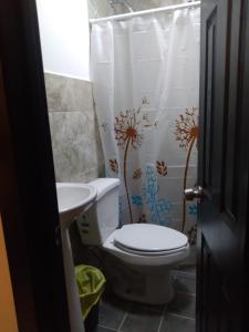 a bathroom with a toilet and a sink and a shower curtain at Departamentos velasco in Tijuana