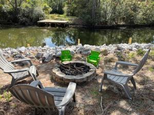 three chairs and a fire pit in front of a pond at Waterfront Newly Renovated and Decorated 3brs home in Milton