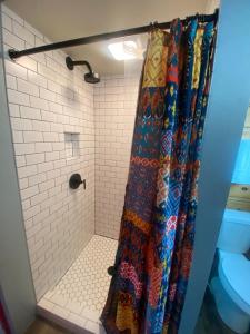 La salle de bains est pourvue d'une douche avec un rideau de douche coloré. dans l'établissement SkyWater Cabins, à Hamilton