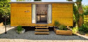 Nefoedd Romantic Shepherds Hut في سوانسي: منزل صغير صغير أصفر صغير مع باب مفتوح