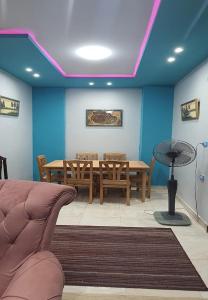 uma sala de jantar com uma mesa e cadeiras e paredes azuis em M&H Apartment em Dumyat al Jadidah