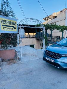 a car parked in front of a house with a sign at huseein rooms in Jerash