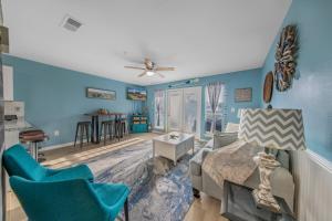 Grand Caribbean in Perdido Key 111E by Vacation Homes Collection في بينساكولا: غرفة معيشة بجدران زرقاء وأريكة وكراسي