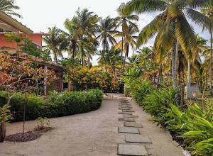 una pasarela con palmeras y plantas frente a un edificio en CasAmar Pé na Areia em Condomínio Beira Mar, en Serra Grande