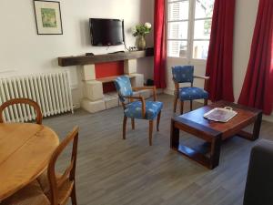 - un salon avec une table, des chaises et une télévision dans l'établissement Côté Château, à Chinon
