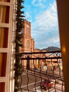 une fenêtre donnant sur un bâtiment avec une tour d'horloge dans l'établissement Hotel La Casa Ovalle, à San Vicente de Chucurí