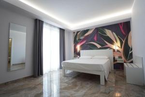 ein Schlafzimmer mit einem weißen Bett und einem farbenfrohen Gemälde in der Unterkunft Harmony Tropea Rooms & Suites in Tropea