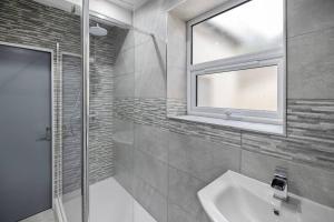 a bathroom with a sink and a window and a shower at Brand New Huge 2 Bedroom Ground Floor Flat in Plymouth