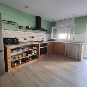 Una cocina con paredes verdes y gabinetes de madera. en Casa FotoStudi37, en Deltebre