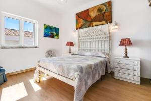 a bedroom with a white bed and a painting on the wall at Tavira Balsa Romana - Luz de Tavira in Luz de Tavira