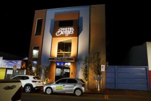 two cars parked in front of a building with a store at Hotel Borges in Quirinópolis